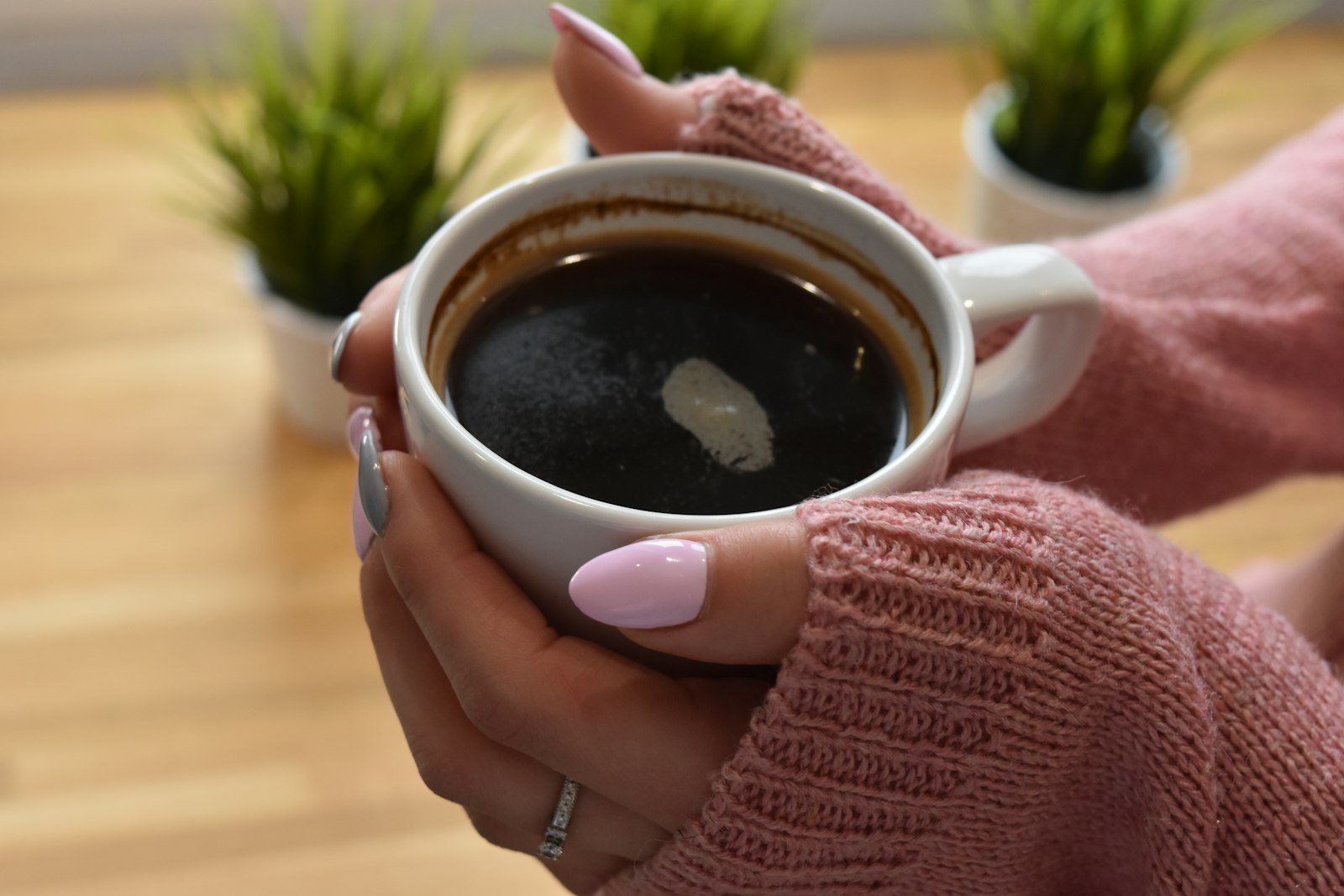 Hands cradling a warm mug, mother in soft light